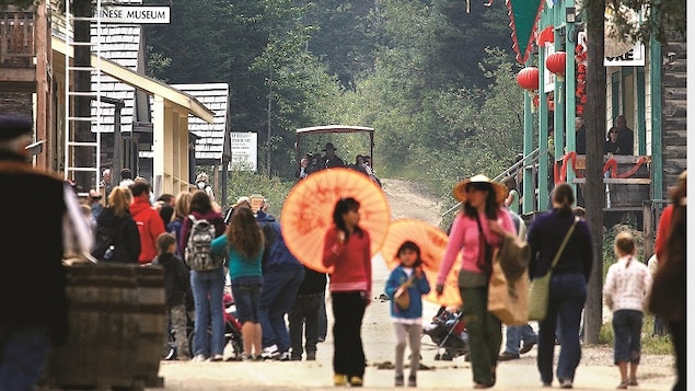 People walking down Barkerville's main street with Asian umbrellas.