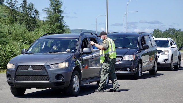 Un agent au point de contrôle discute avec un automobiliste dans une file d'attente.