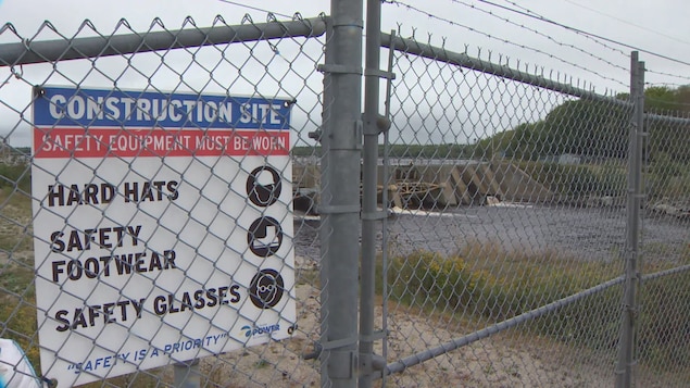 Image d'une affiche de sécurité de construction sur une clôture devant le barrage de la rivière tusket.
