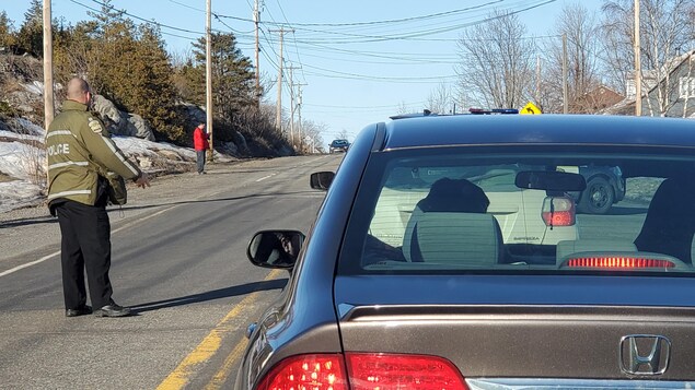 Des voitures arrêtées et un policier sur la route.