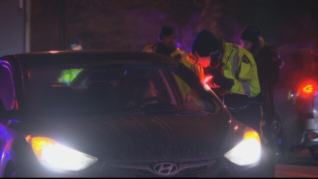 Un policier parle à une conductrice arrêtée dans un barrage routier à Ottawa Un policier parle à une conductrice arrêtée dans un barrage routier à Ottawa