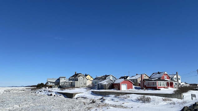 Plusieurs maisons sur le bord du fleuve glacé.