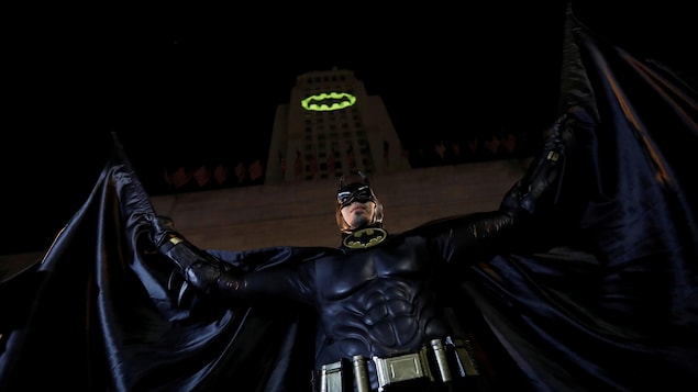 Une personne déguisée en Batman prend la pose devant une projection sur l'hôtel de ville de Los Angeles, en Californie, en hommage à l'acteur Adam West qui incarnait le personnage. Une personne déguisée en Batman prend la pose devant une projection sur l'hôtel de ville de Los Angeles, en Californie, en hommage à l'acteur Adam West qui incarnait le personnage.