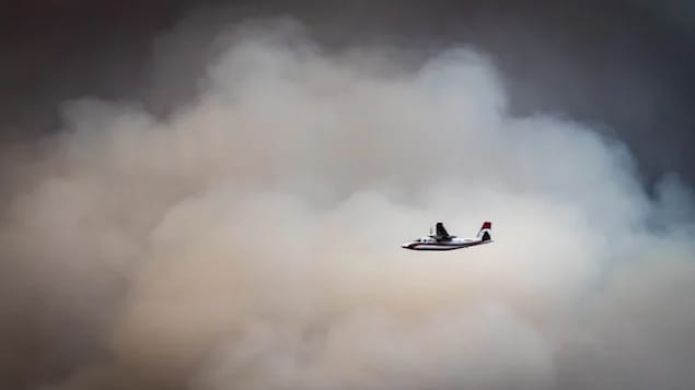 An aircraft flies through smoke on July 19 as it works to tame the Nk'Mip fire, which has forced evacuations in the southern Okanagan Valley.