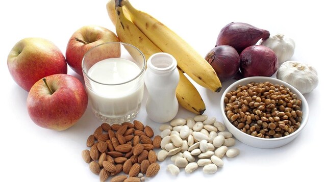 Des pommes, un verre de lait, des yogourts, des amandes, des oignons et de l'ail sur un fond blanc. Des pommes, un verre de lait, des yogourts, des amandes, des oignons et de l'ail sur un fond blanc.