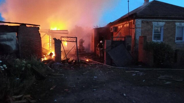 Des pompiers sont à l’œuvre pour éteindre le feu dans une maison après un bombardement.