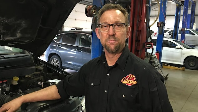 Jean-Paul Belliveau inspecte le moteur d'une voiture Jean-Paul Belliveau inspecte le moteur d'une voiture
