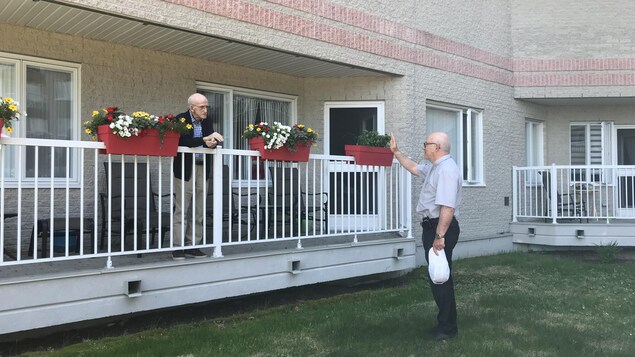 René Guay salue un homme qui est sur son balcon.