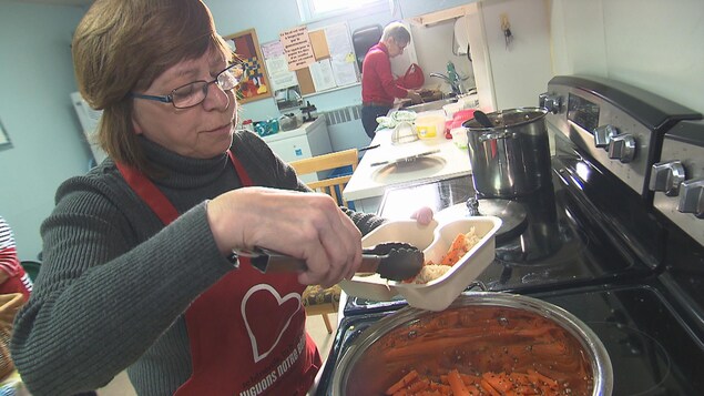Des bénévoles dans une cuisine collective préparent des repas.