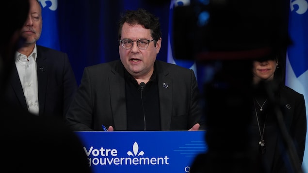 Le ministre de l'Éducation du Québec, Bernard Drainville, devant un micro.
