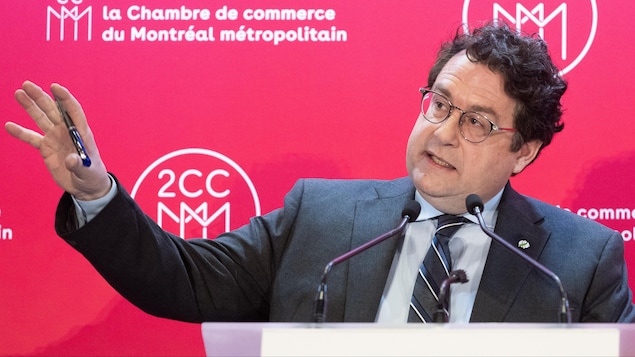 Le ministre de l'Éducation du Québec, Bernard Drainville, parle au micro devant une affiche de la Chambre de commerce de Montréal.