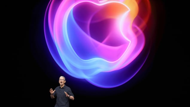 蒂姆-库克（Tim Cook）站在苹果公司的徽标前。
