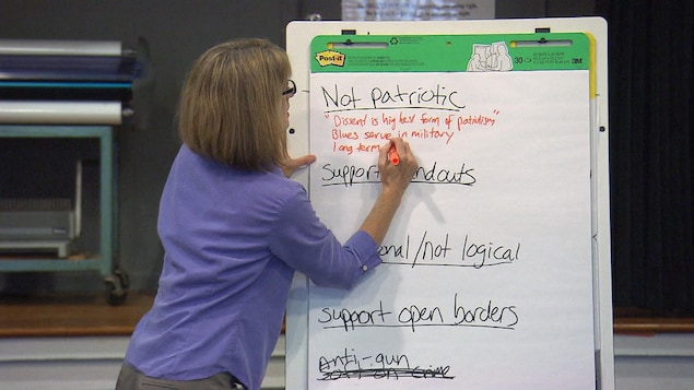 Une femme écrit sur un tableau des expressions en anglais: «non patriotique», «illogiques», notamment.