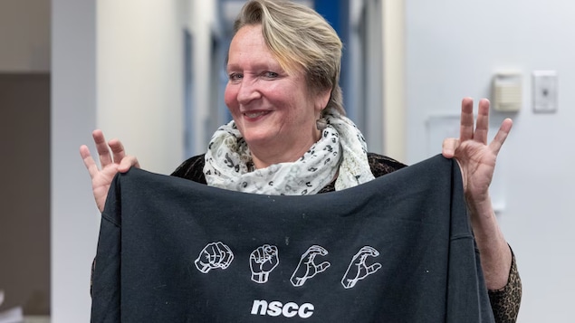 Beverly Buchanan tient un chandail montrant NSCC en langage signé.
