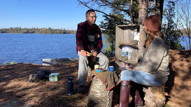 Charles Sagalane discute avec la journaliste Julie Larouche sur les rives du Lac-Saint-Jean.