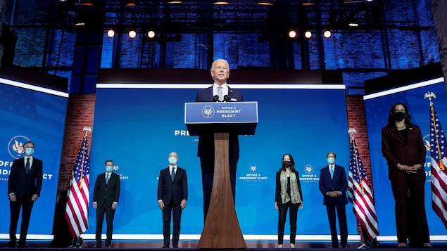 Joe Biden s'adresse aux journalistes en compagnie de ses nouveaux collaborateurs, Antony Blinken, Jake Sullivan, Alejandro Mayorkas, Avril Haines, John Kerry ainsi que la vice-présidente désignée, Kamala Harris, qui portent tous un masque.