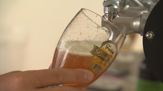 Un gros plan sur une personne qui remplit un verre de bière en fût.