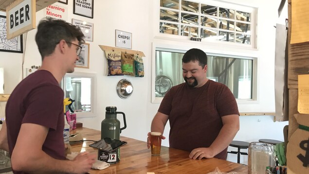 Adam Smith, copropriétaire de la microbrasserie Malty National à Regina, sert une bière à Matt Leisle, un fidèle client.