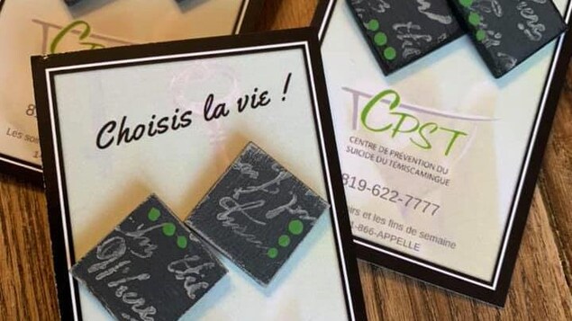 Des boucles d'oreilles de forme carrée sont rassemblées par paire sur un carton.