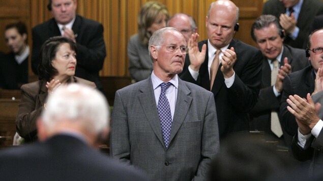 Bill Graham debout en Chambre, alors que les autres députés l'applaudissent.