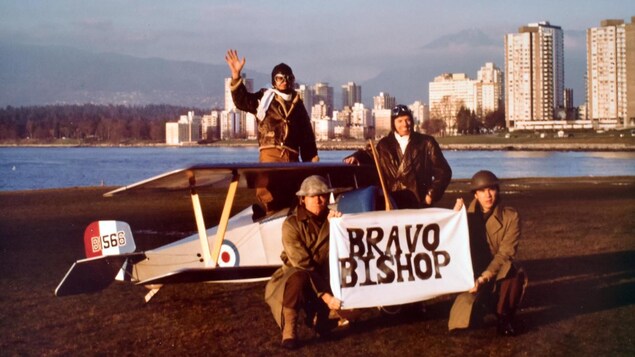 Quatre hommes en costume militaire devant et dans un biplan