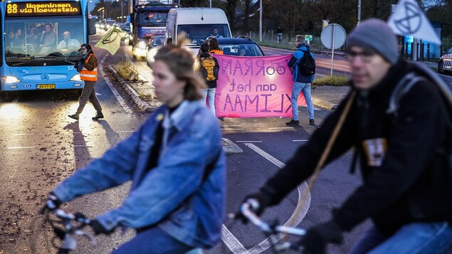 Des militants bloquent la circulation automobile avec des banderoles colorées.