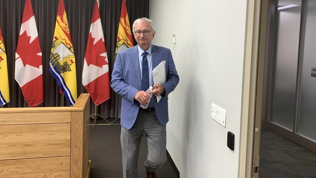 Blaine Higgs quitte un podium, des documents sous le bras.