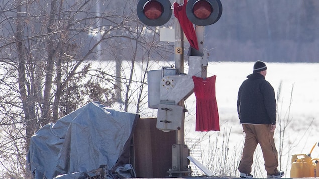 Un homme marche le long de la voie ferrée.