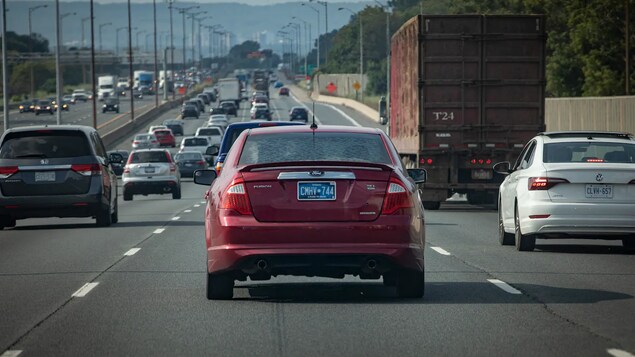 Mga sasakyan sa highway, ang isa may kulay asul na licence plate.