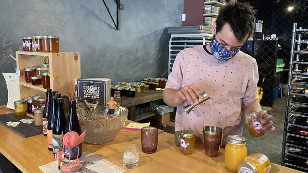 Un homme portant un masque et préparant un cocktail.