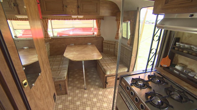 On voit que la caravane contient une table avec des bancs, une porte à gauche est celle des toilettes, et à droite se trouve la petite cuisine. Le tout est dans les tons bruns et dans le style de la fin des années soixante-dix. On voit que la caravane contient une table avec des bancs, une porte à gauche est celle des toilettes, et à droite se trouve la petite cuisine. Le tout est dans les tons bruns et dans le style de la fin des années soixante-dix.