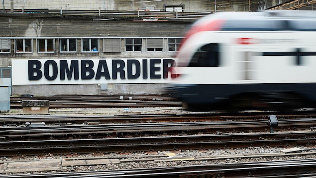 Un train suisse passe devant une publicité de Bombardier placardée sur un mur d'une gare de Berne en Suisse.