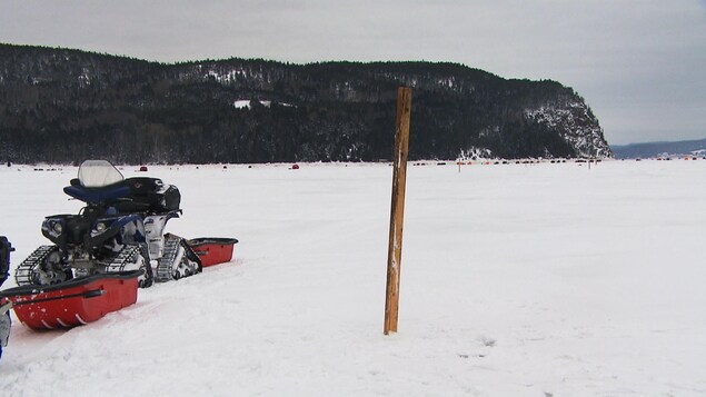 Une motoneige et un poteau de bois sur une baie gelée l'hiver.