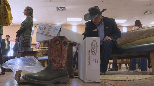 Un homme assis essaie des bottes de cowboys dans le magasin Alberta Boot à Calgary, le 3 mai 2022.
