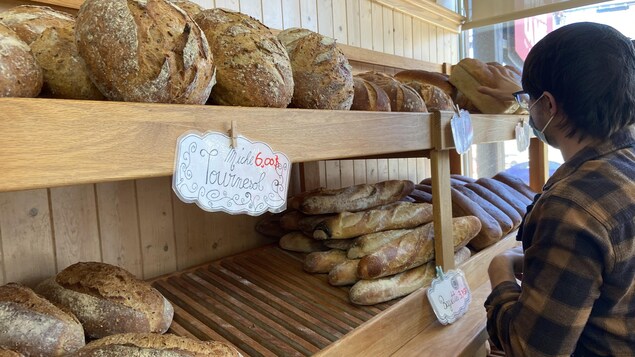 Un boulanger dispose des pains sur une étagère.