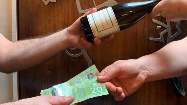Quelqu'un donnant une bouteille de vin et recevant des billets de banque.