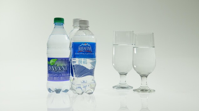 Trois bouteilles d'eau et deux verres d'eau. 
