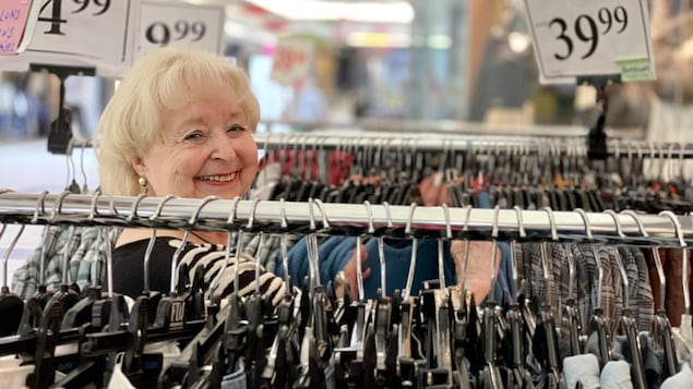 Une dame sourit dans un un magasin de vêtements