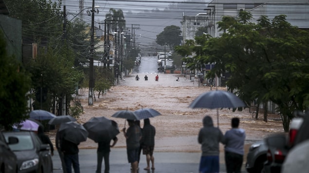 Des habitants observent une rue inondée dans le centre-ville.