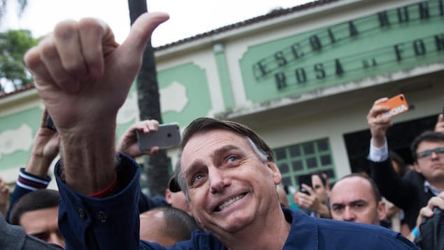 Dans la foule, Jair Bolsonaro lève son pouce en l'air en signe de victoire.