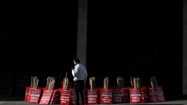 Un manifestant se tient à côté d'affiches à distribuer dans le cadre de la manifestation anti-Brexit de samedi, dans le centre de Londres. Un manifestant se tient à côté d'affiches à distribuer dans le cadre de la manifestation anti-Brexit de samedi, dans le centre de Londres.