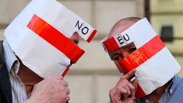 Deux hommes munis de casques aux couleurs du drapeau anglais discutent.