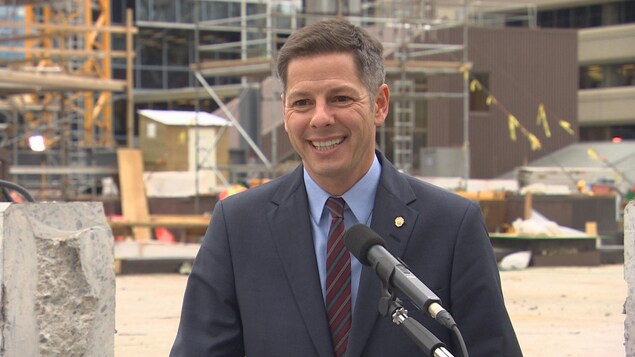 Brian Bowman, souriant, à l'extérieur, devant un chantier de construction. Brian Bowman, souriant, à l'extérieur, devant un chantier de construction.