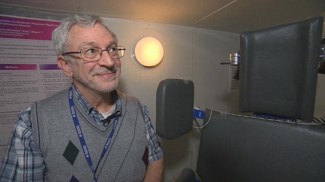 Un homme regarde la caméra en souriant. Il se tient près d'un fauteuil utilisé pour effectuer le test dont il parle.