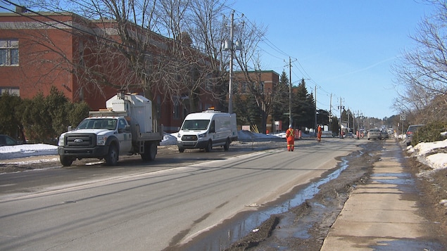 Des employés travaillent dans une rue près de camionnettes municipales en hiver.