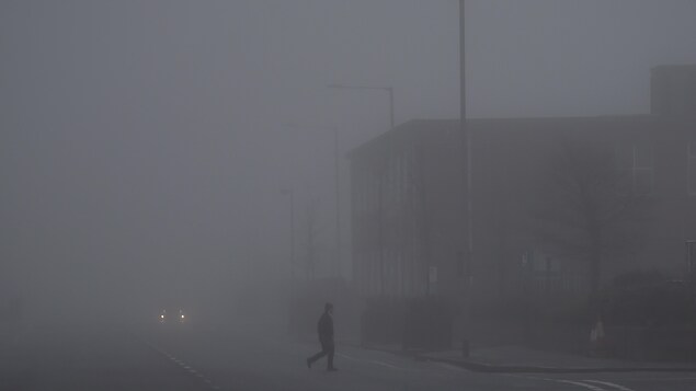 Un homme marche dans une rue de Belfast recouverte de brouillard. Un homme marche dans une rue de Belfast recouverte de brouillard.