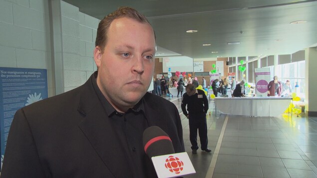 Un homme en veston d'affaire dans un atrium en entrevue au micro de Radio-Canada. Un homme en veston d'affaire dans un atrium en entrevue au micro de Radio-Canada.