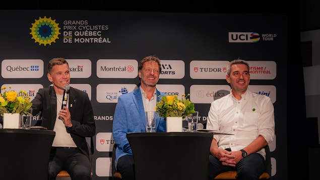 Les trois hommes sont assis l'un à côté de l'autre en conférence de presse. 