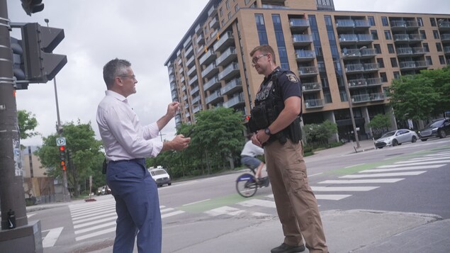 Un animateur et un policier debout à une intersection routière.