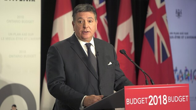 Photo de Charles Sousa derrière un podium rouge portant la mention Budget 2018. Photo de Charles Sousa derrière un podium rouge portant la mention Budget 2018.